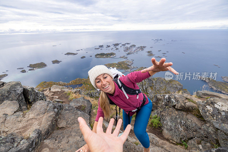 徒步旅行者帮助队友到达山顶