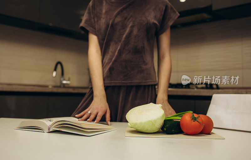 年轻女子在厨房里阅读烹饪书，寻找食谱