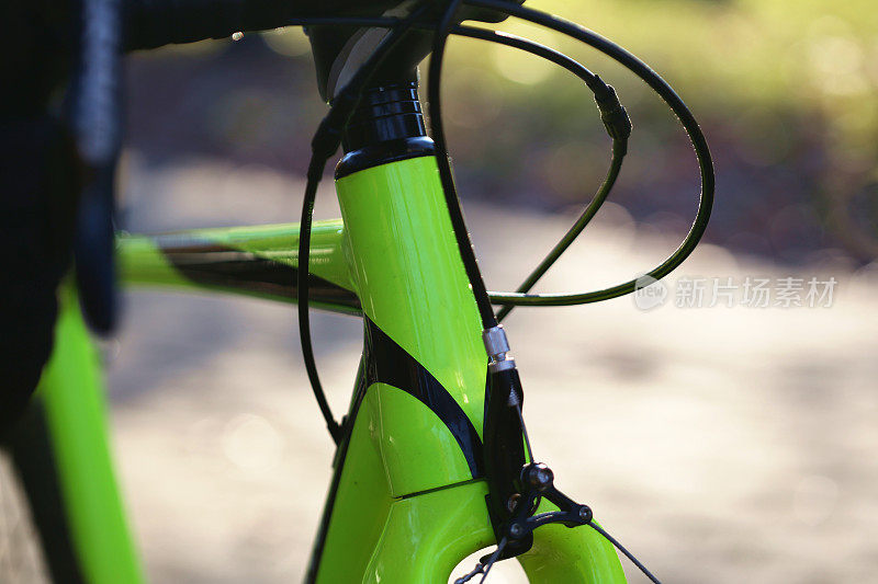 自行车车架特写(自行车头管与齿轮和制动电缆，换档器，耳机垫片)黄绿色孤立微距镜头与太阳辉光