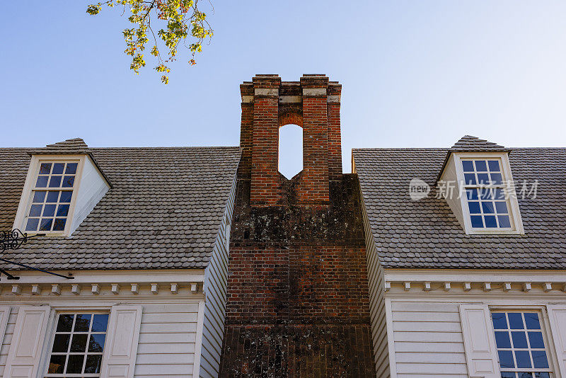 弗吉尼亚州威廉斯堡殖民地时期，一排排房屋之间的砖砌烟囱映衬着蓝天。低角度视图