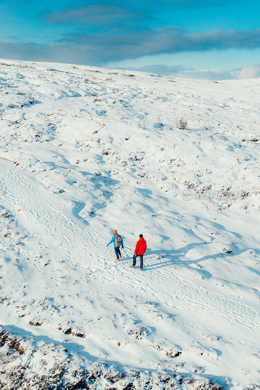 鸟瞰图的女人和男人考虑徒步旅行在雪山与湖景在挪威