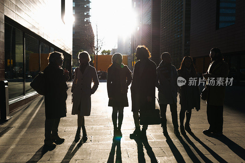日落时分，一群商人站在金融区的大街上互相交谈。