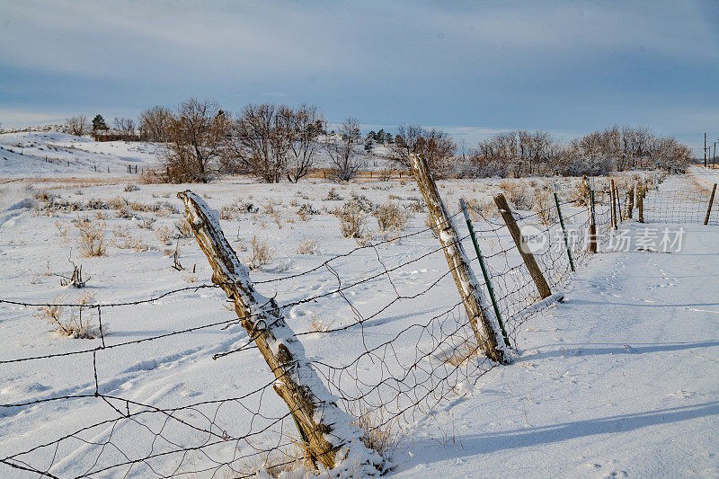 在蒙大拿雪天路上，牧场的篱笆柱子倾斜着