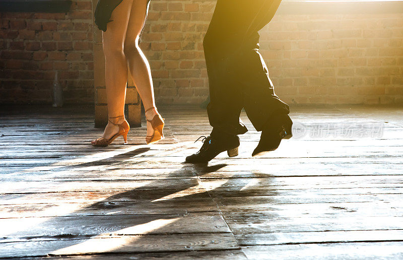 两名职业交际舞舞者的两条腿正在阁楼工作室跳舞。美丽的艺术表演伴随着浓重的烟雾。运动生活的概念。激情和情感的舞蹈。
