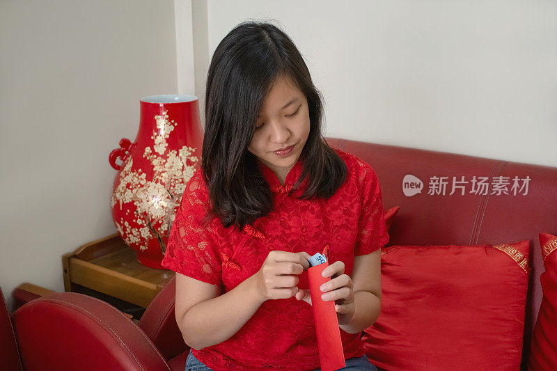 年轻的亚洲妇女正在打开她的红包