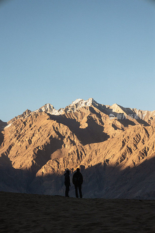 夕阳西下时，男人们在山的背景上沉思