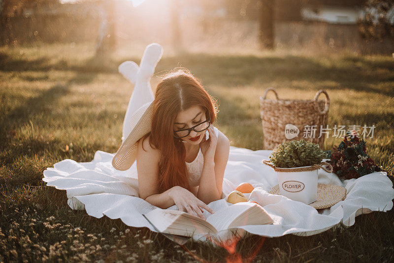 美丽的女孩在大自然中穿着白衣看书。