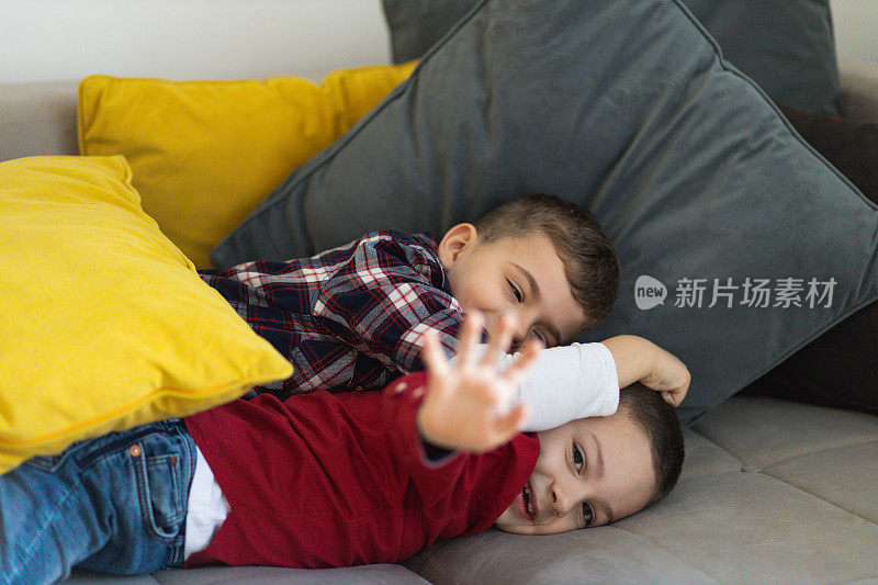 两个可爱的小男孩在沙发上打架