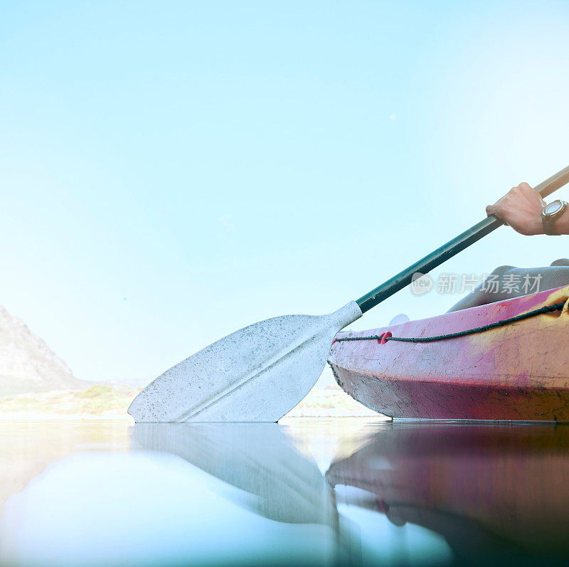特写皮划艇桨划动在平静的水面上。女人们在暑假期间在湖上划皮艇。在大自然中享受水上活动的女人。为皮划艇比赛进行训练和练习