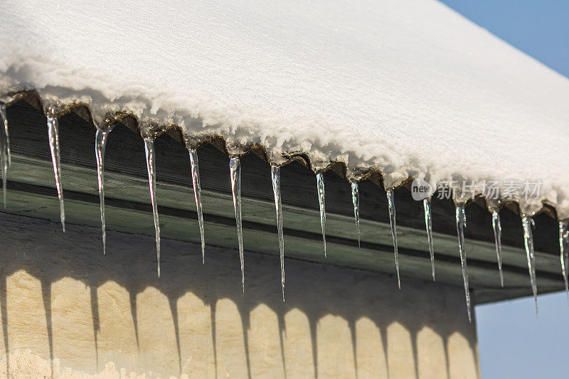 冰柱挂在屋顶上。冬天的背景。天气。气候。冰