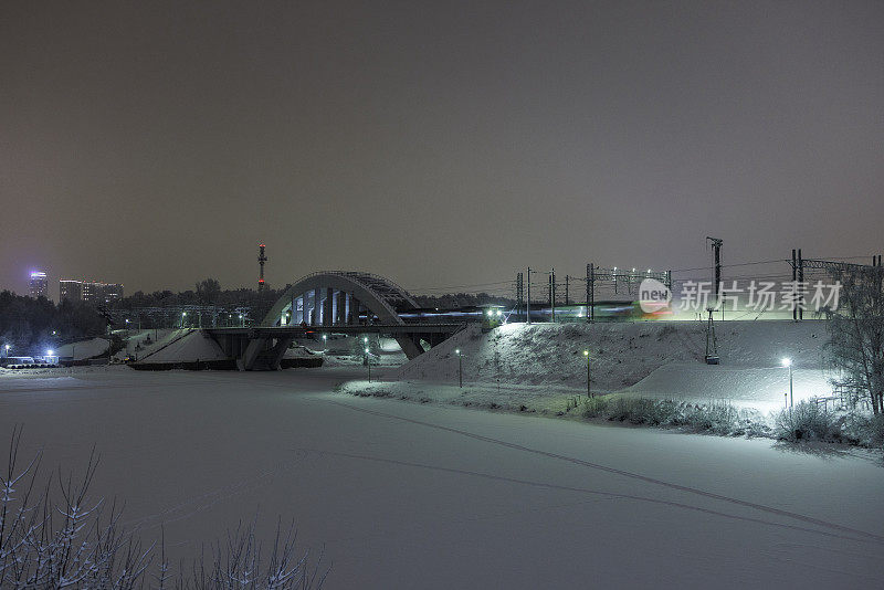 在俄罗斯莫斯科地区Khimki的冬季公园里，Tain正在经过一座桥，桥上是结冰的河流。