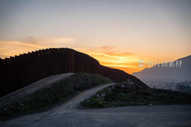 加利福尼亚特卡特和墨西哥特卡特之间的国际边界墙，靠近下加利福尼亚北部蒂华纳的黄昏，在令人惊叹的日落下，从美国俯瞰城市