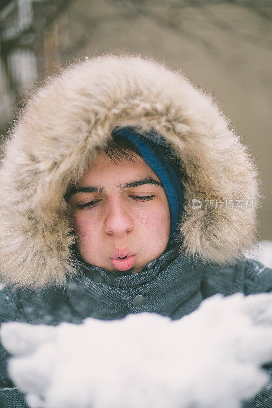 冬天的一天，男孩从他的手上吹雪