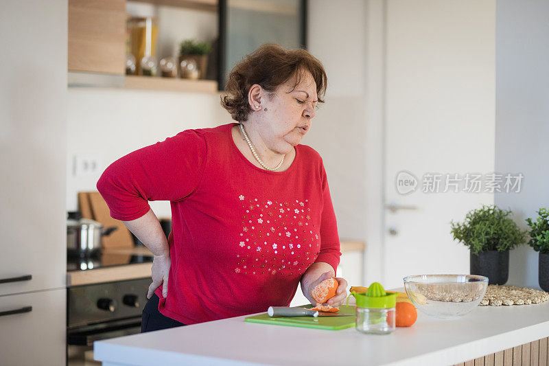 一名老年妇女正在吃橘子，感到腰痛