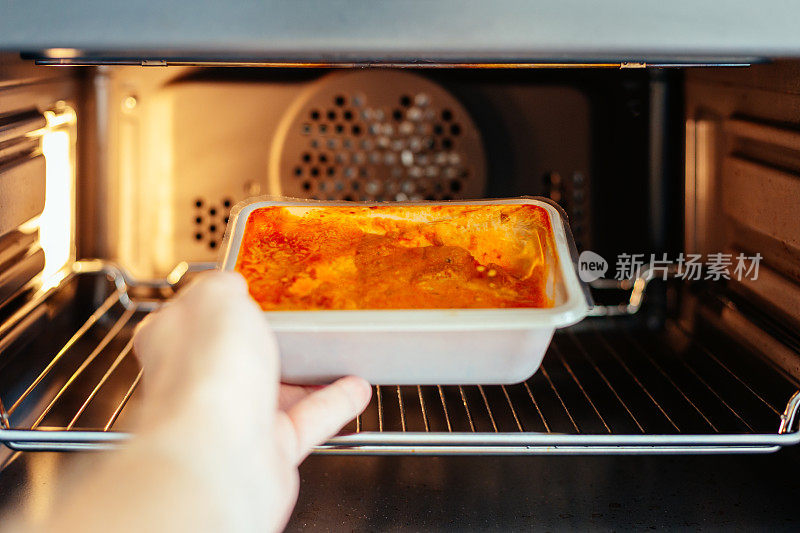 男人把现成的饭菜放进家里的微波炉里