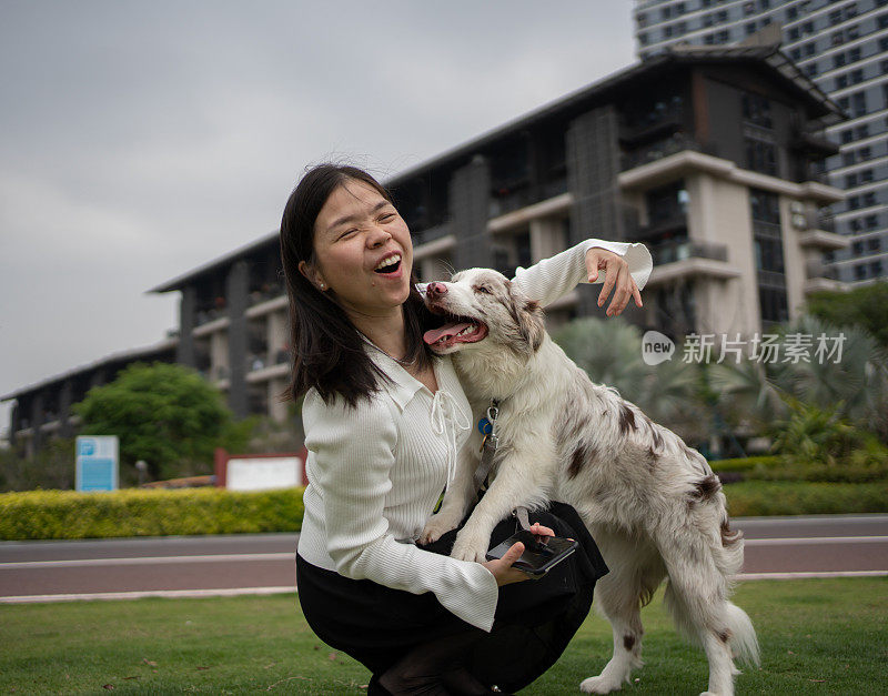 一名妇女在户外与柯利牧羊犬玩耍