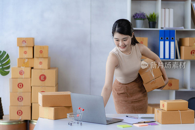 迷人的亚洲女人开始一个小生意，中小企业企业家，配送仓库与邮箱。业主的小型家庭办公室在线营销和产品包装及送货上门服务。