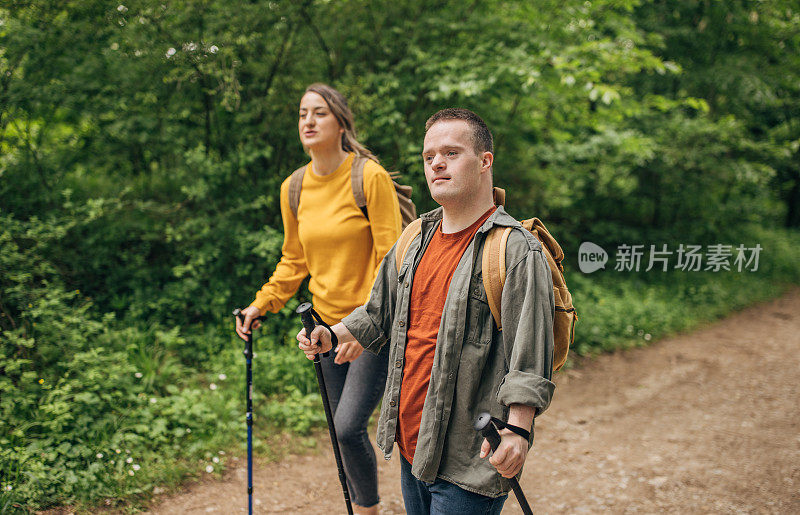 两个朋友，一个年轻的女人和一个患有唐氏综合症的男人，一起在森林里远足