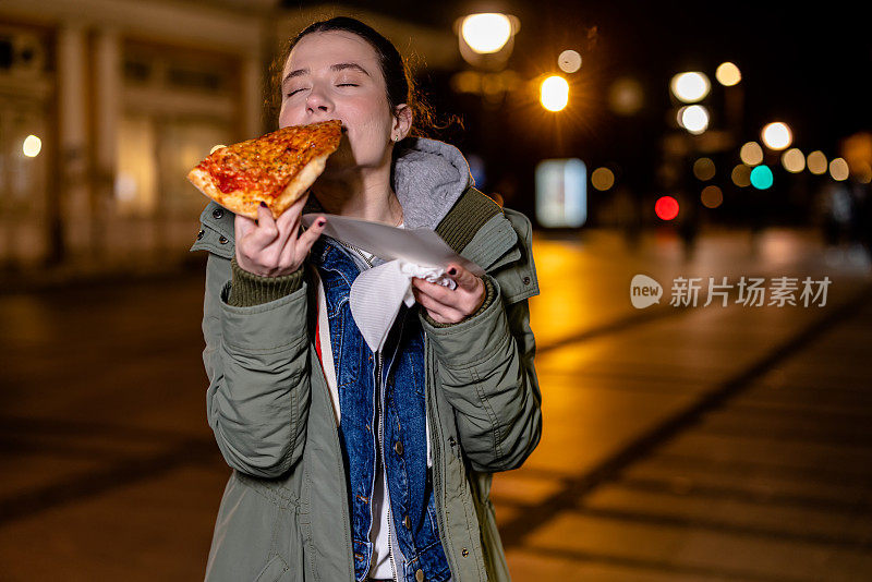 年轻女子在街上满足了她对披萨的渴望