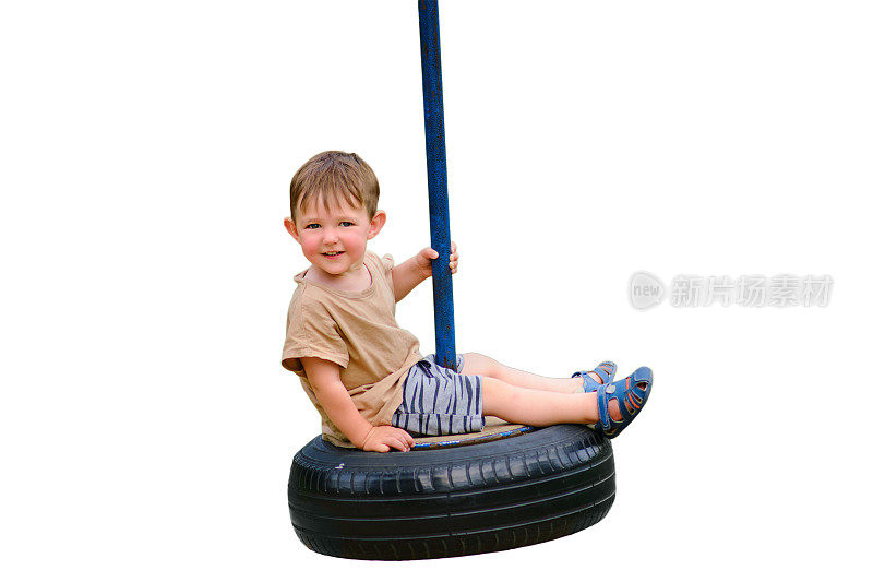 一个微笑的孩子喜欢玩一个汽车轮胎变成秋千，孤立在白色的背景。一个快乐的婴儿正在用汽车轮子的轮胎做成的秋千上旋转。两岁儿童