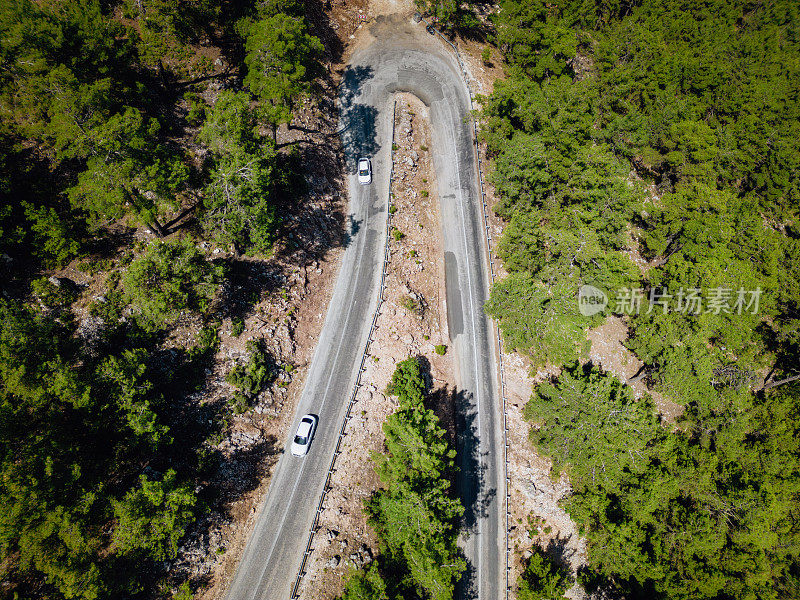 在森林山区的道路上行驶的车辆用无人机拍摄沥青弯道