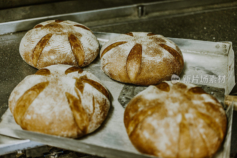 烤面包。面团放在木桌上的打样篮里，与面粉、孜然和麦穗放在一起。前视图。