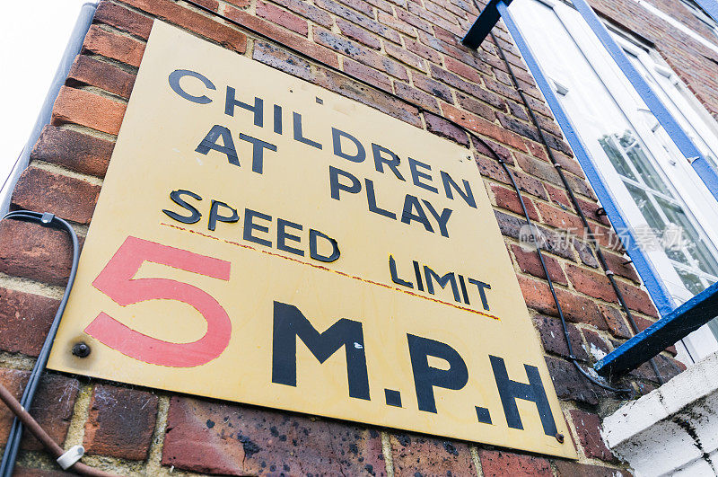 标志警告司机有孩子在玩耍，并强制执行每小时5英里的限速。