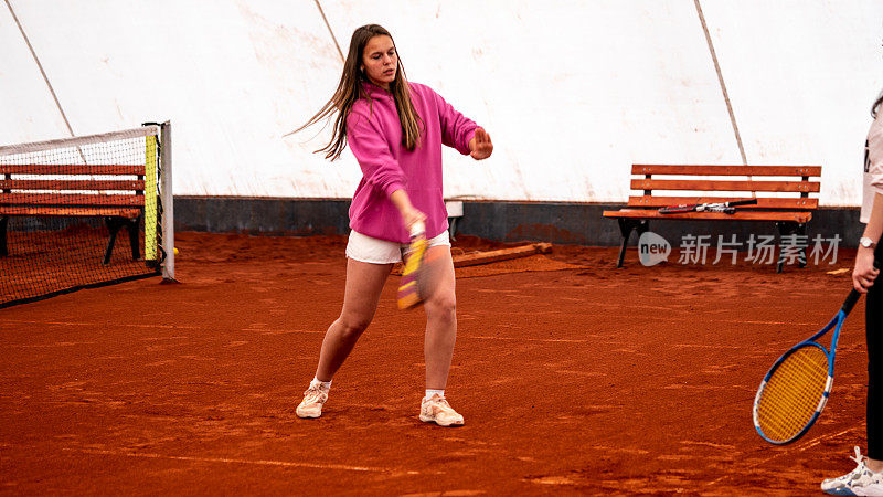金发女子网球教练还在红土场上教正手水平女子运动员运动