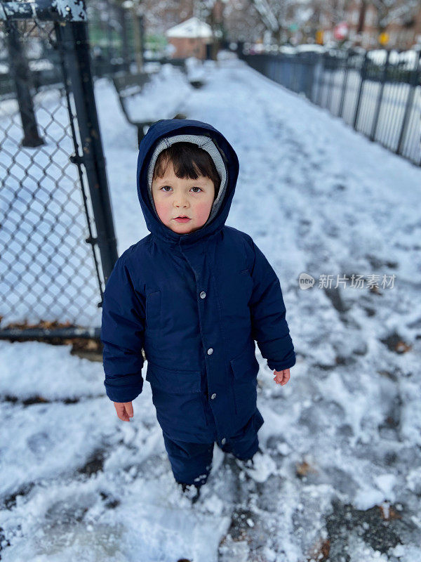 一个男孩站在公园的雪地里