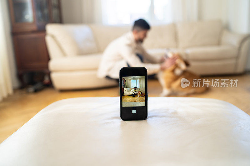 一名男子正在用智能手机摄像头和他的狗狗一起拍摄舞蹈视频