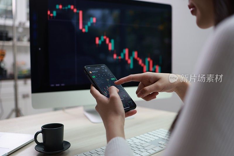 女商人研究金融市场来计算可能的风险和利润。投资应用程序在计算机屏幕上显示股票市场图表并建议交易决策。