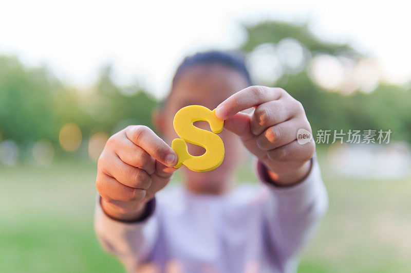 儿童手持字母“S”