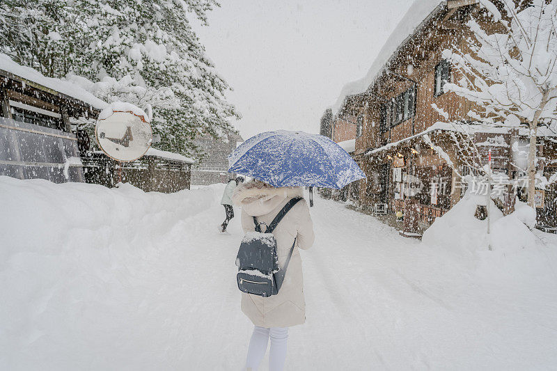 美丽的女游客享受他们的旅行白川古村在日本的冬天厚雪