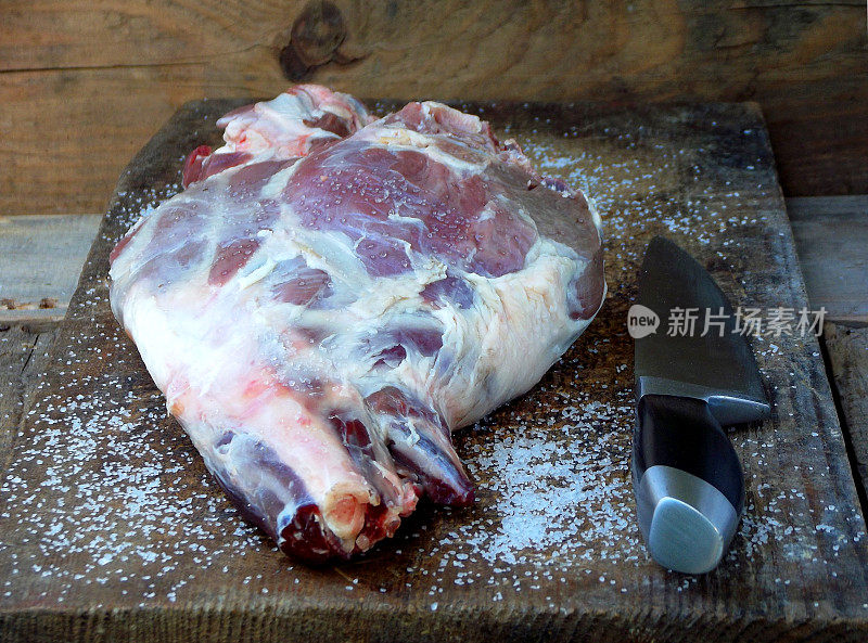 新鲜的生肉。用刀放在木板上的羊腿，用于烤、炖、肉饭、烤肉、烤肉串、什锦饭
