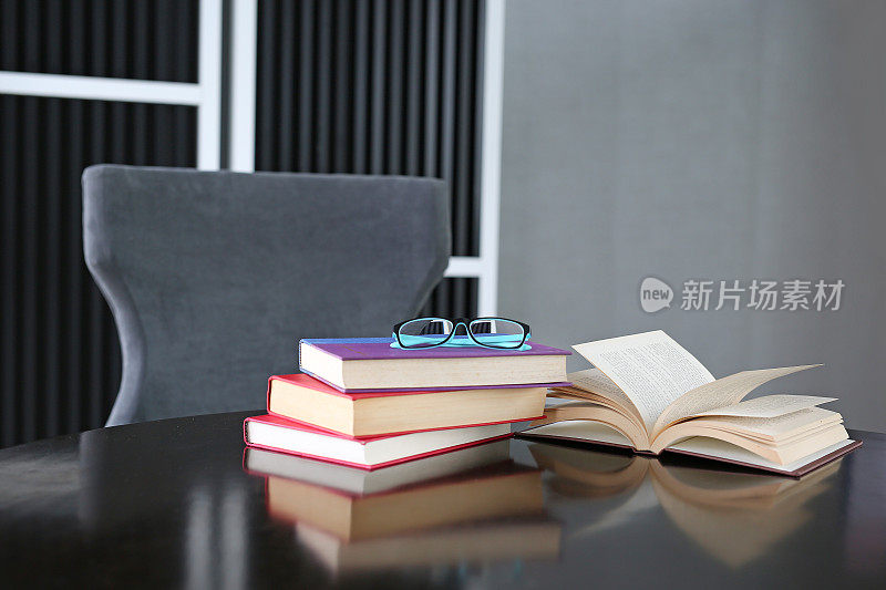 戴眼镜的木桌上放着精装书。教育背景。