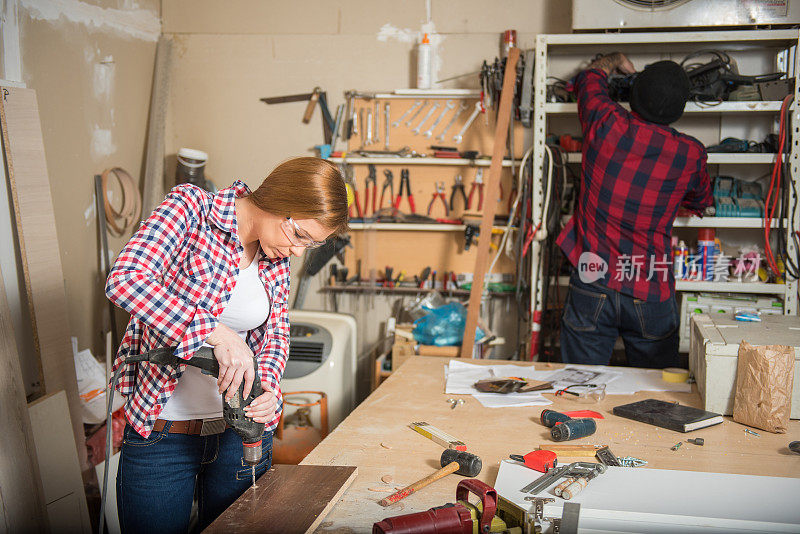 女人和男人在木工车间使用电动工具