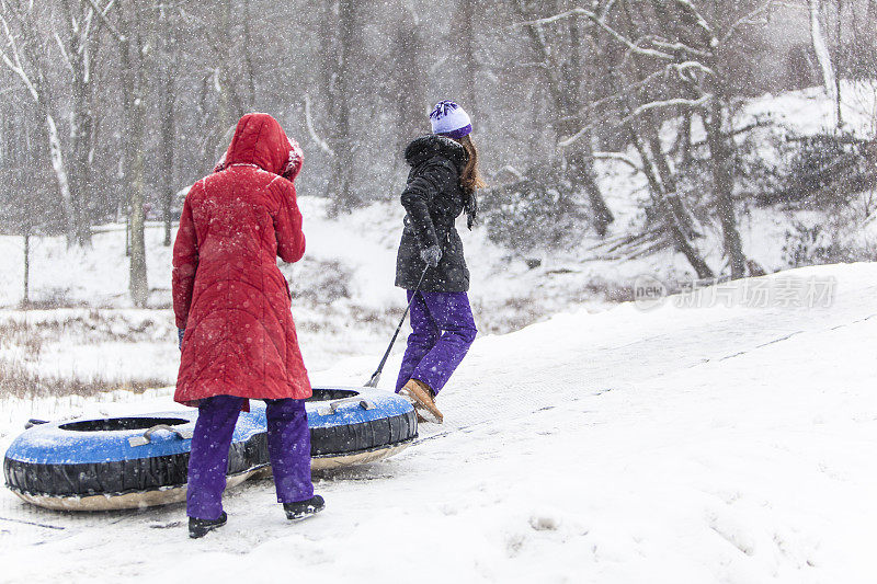 Snowtubing。两个女孩要去山顶