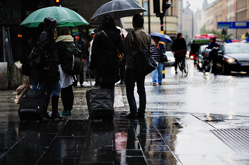 行人撑着雨伞穿过雨湿的街道