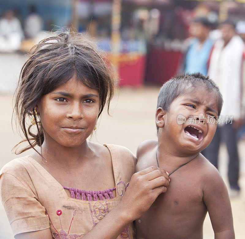 印度兄弟姐妹漂亮的女孩抱着哭闹的小弟弟。