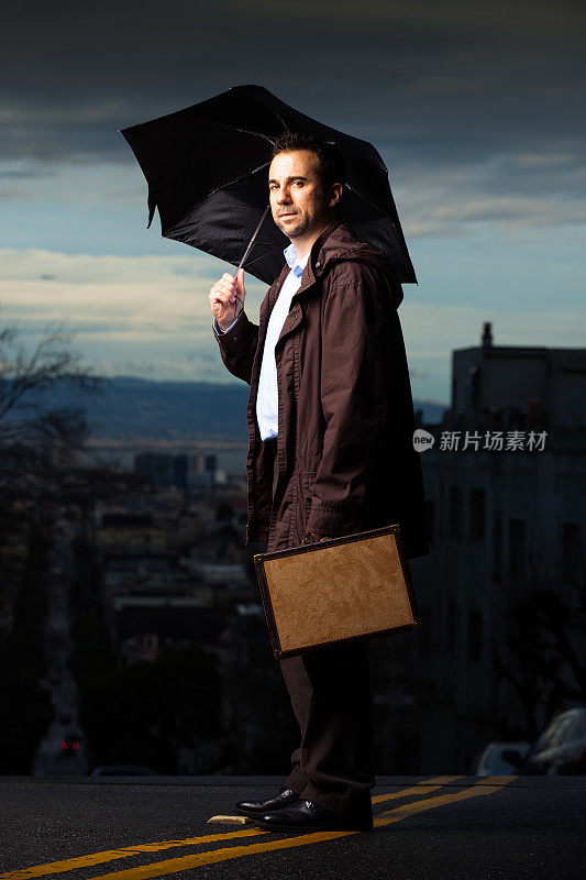 街上拿着雨伞和公文包的男人