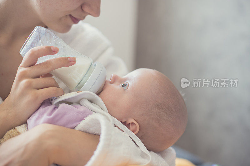 一个婴儿在母亲怀里喝牛奶的特写