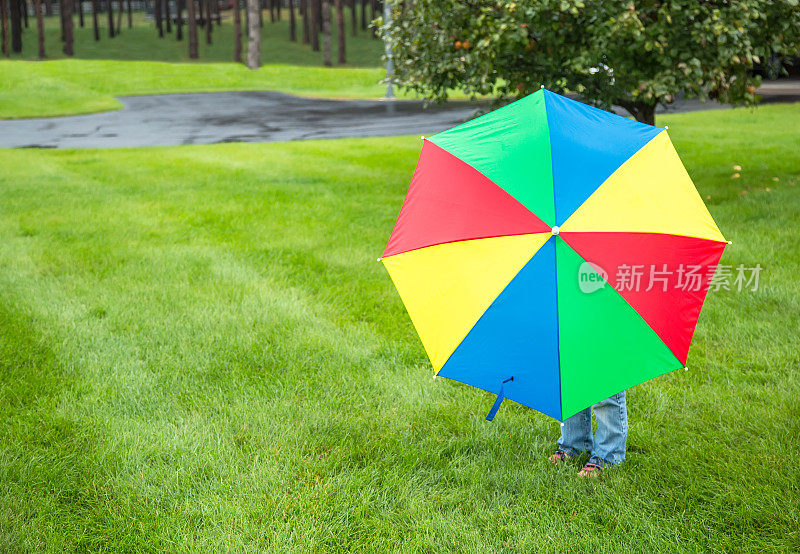 站在彩色雨伞后面的孩子