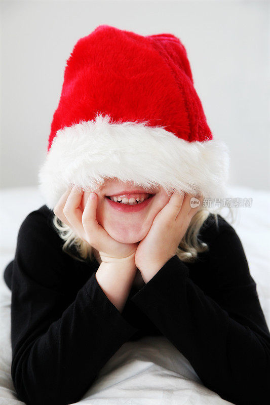 可爱的小女孩戴着圣诞老人的帽子遮住她的眼睛