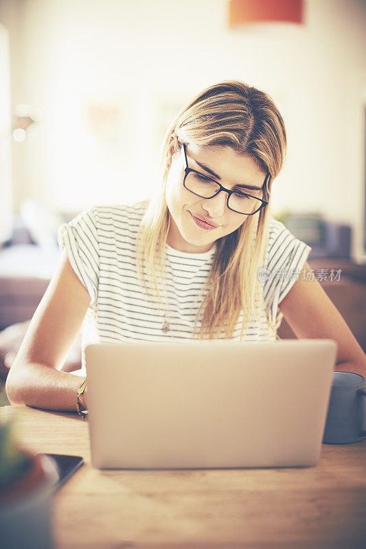 年轻时髦的女人在使用笔记本电脑时戴着眼镜