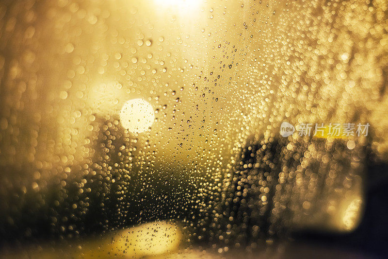 抽象的夜晚明亮的灯光透过模糊的雨车窗