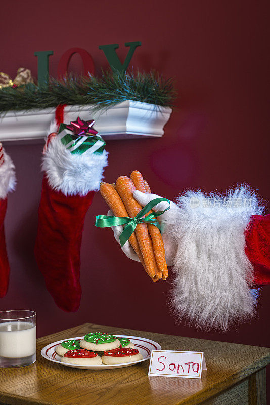 圣诞老人拿着一堆胡萝卜给他的驯鹿