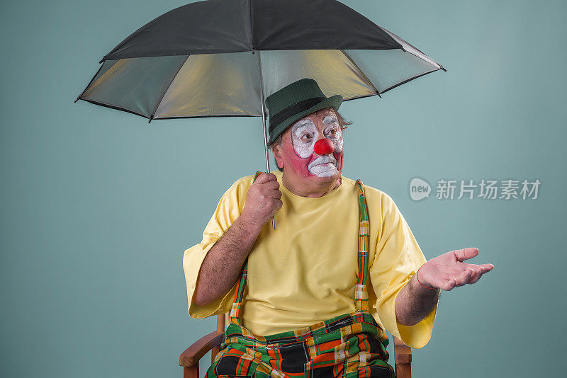 年老的小丑拿着伞