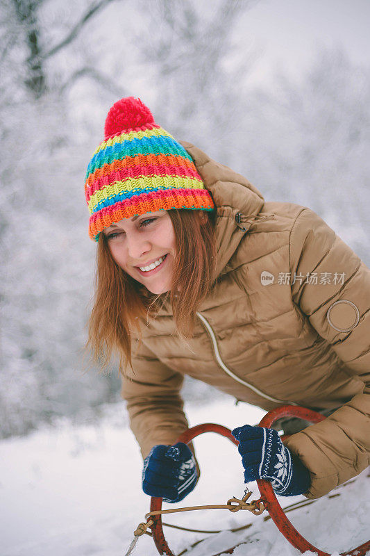 快乐的年轻女子在一个快速的雪橇骑下冰冷的斜坡