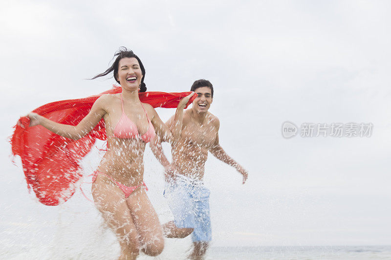 新婚夫妇蜜月时在海滩上跑步