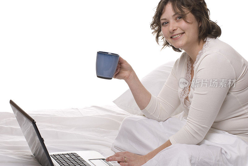 在床上用笔记本电脑喝咖啡